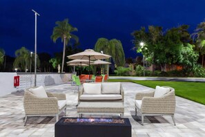 Un espacio al aire libre con muebles de mimbre, un hogar y sombrillas.