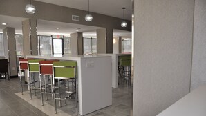 Un espace bar moderne avec des tabourets hauts et un comptoir blanc.