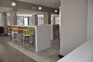 A modern bar area with high stools and a white counter.
