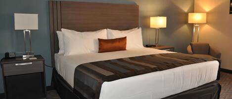 Una habitación de hotel con una cama grande, dos mesitas de noche y dos lámparas de pared.