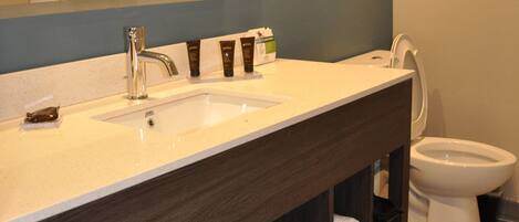 Une salle de bain avec un grand miroir, un lavabo, des toilettes et une étagère avec des serviettes.