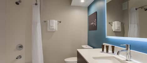 A modern bathroom with a bathtub, shower, toilet, and a vanity with a sink and mirror.