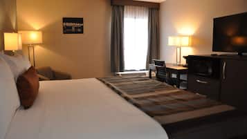 Una habitación de hotel con una cama grande, dos lámparas de noche, un televisor de pantalla plana, un escritorio con silla y una ventana con cortinas.