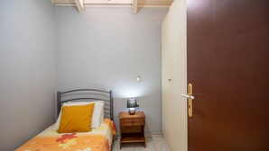 A bedroom with a bed, a nightstand with a lamp, a door, and a window. - Home Away Junior Suite (Zakynthos)