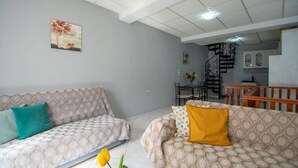 A living room with patterned sofas, a yellow tulip, and a staircase leading to a dining area. - Home Away Junior Suite (Zakynthos)