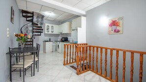 A modern kitchen with white cabinets, a built-in oven, and a dining area with a table and chairs. - Home Away Junior Suite (Zakynthos)