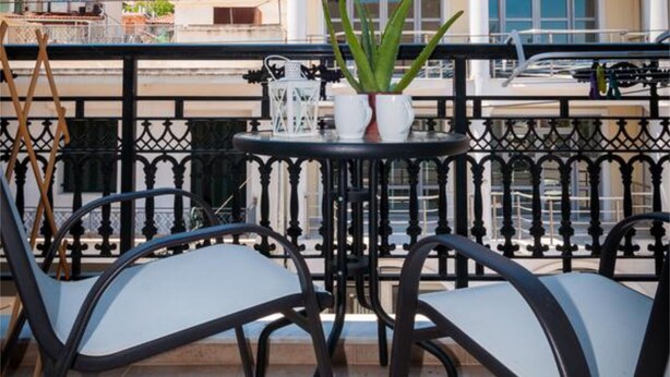 A balcony with a table, chairs, and a potted plant. - Home Away Junior Suite (Zakynthos)