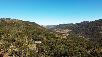 Un paysage montagneux, avec une forêt dense et un petit bâtiment au premier plan.