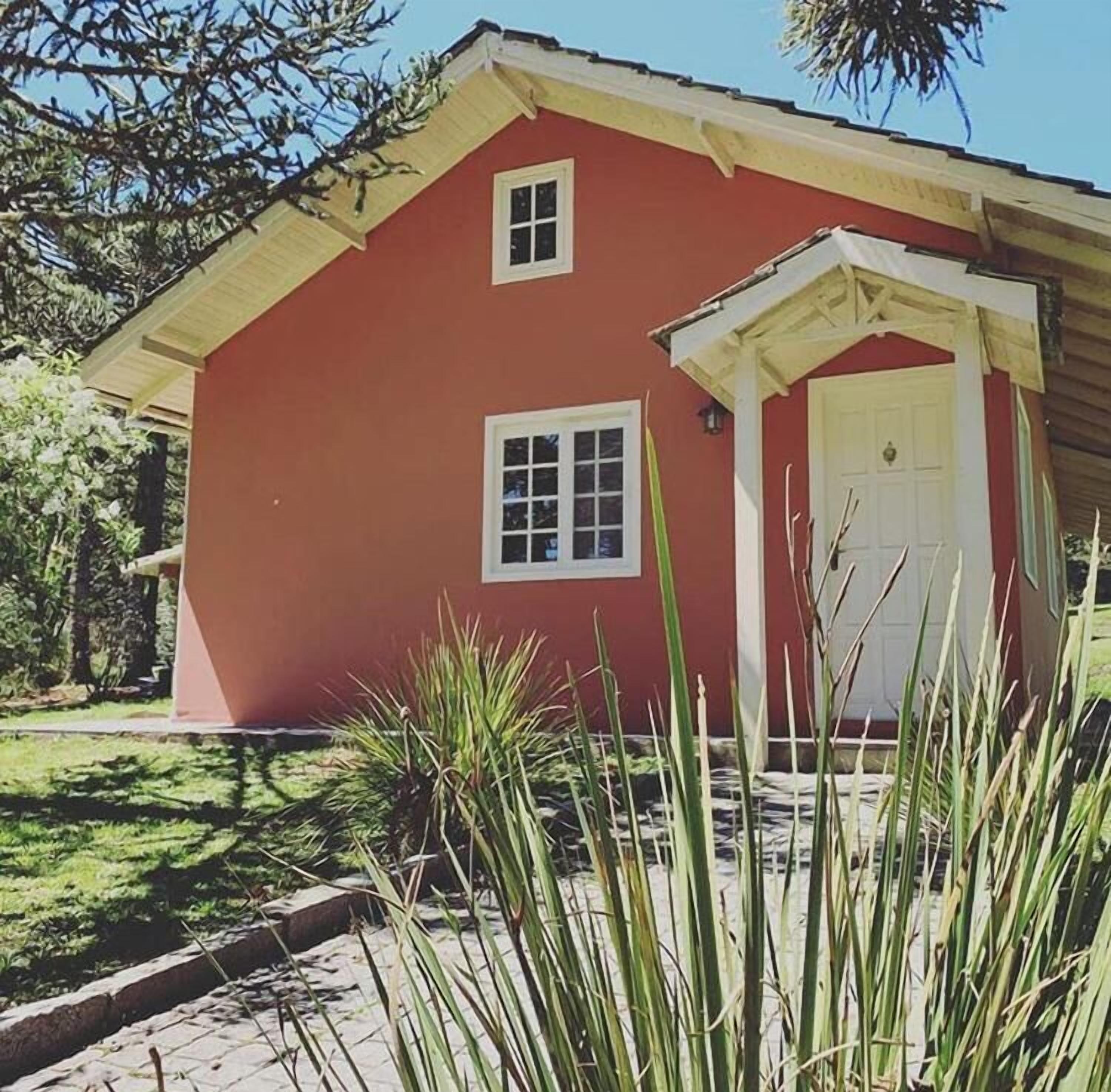Un bâtiment rouge avec une porte blanche et deux fenêtres.