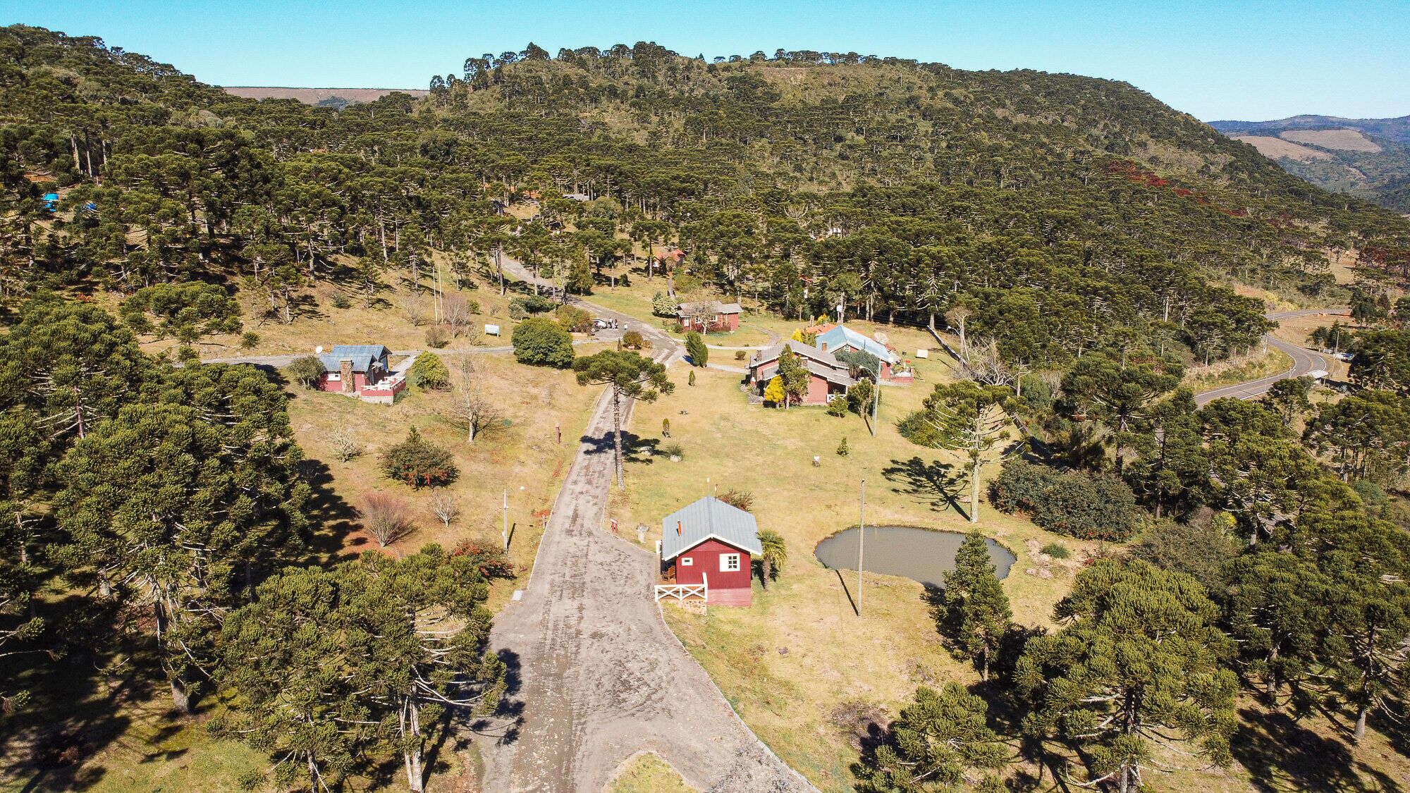 A rural landscape with scattered houses, a winding road, and a small body of water.