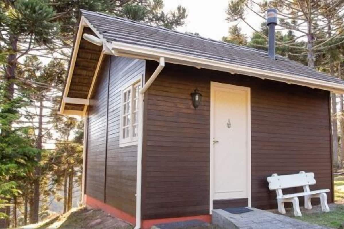 Une petite cabane en bois avec une porte blanche, un banc à l’extérieur et une antenne parabolique sur le toit.