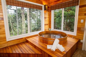 Un sauna en bois doté d’une grande fenêtre, d’un banc en bois et d’une serviette posée sur le banc.