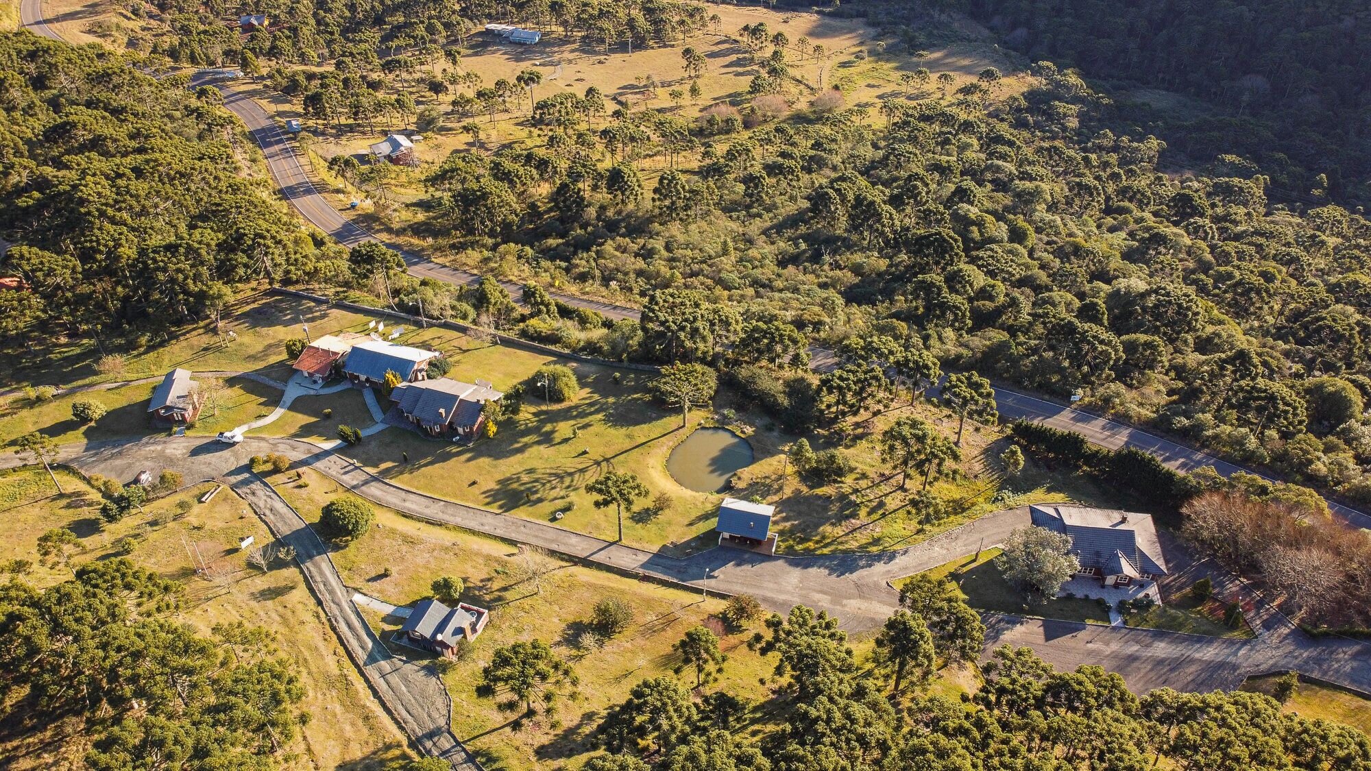 An aerial view of a rural property with multiple buildings, roads, and a large wooded area.