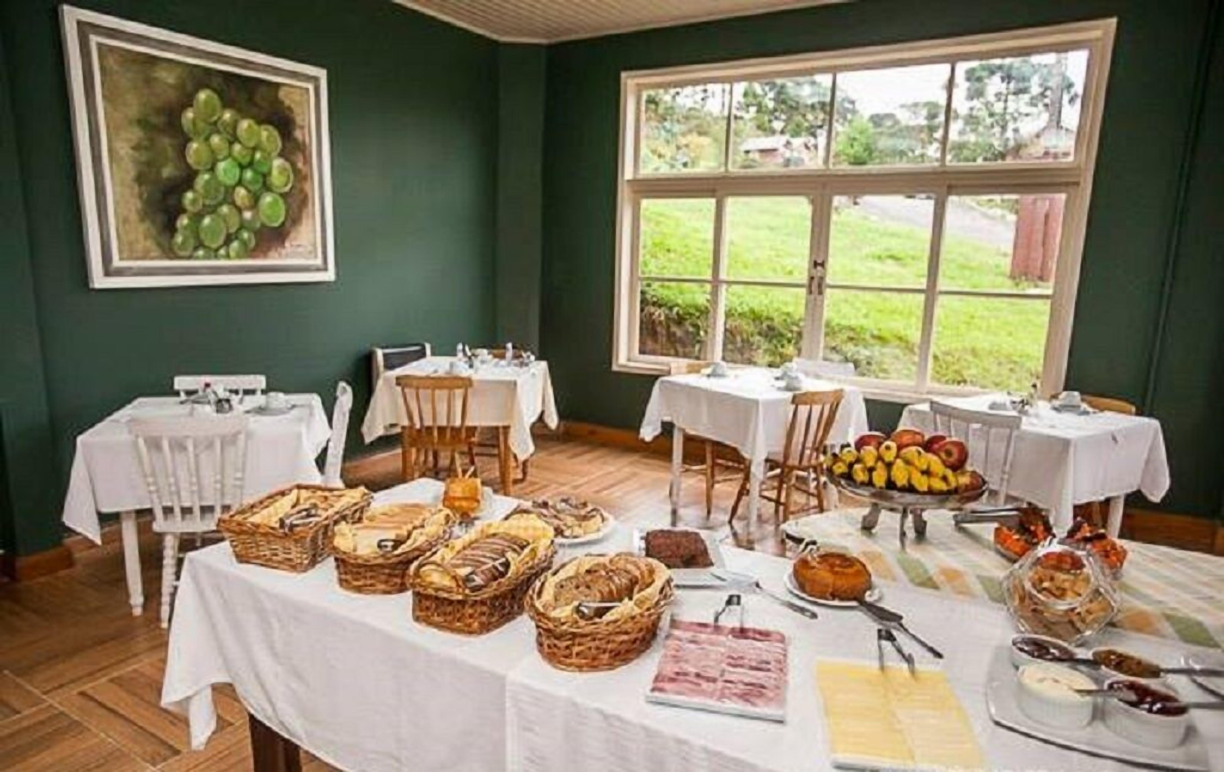 A breakfast buffet with various food items and baskets, set in a room with large windows and a green wall.