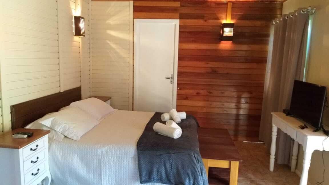 A bedroom with a bed, bedside table, TV, and wooden walls.