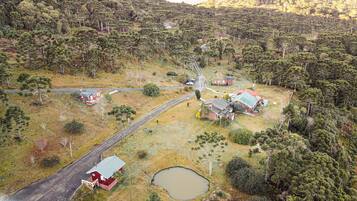 Un paisaje rural con casas dispersas, un camino sinuoso y un pequeño estanque.