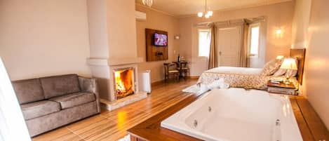 A room with a fireplace, a sofa, a bed, and a TV.