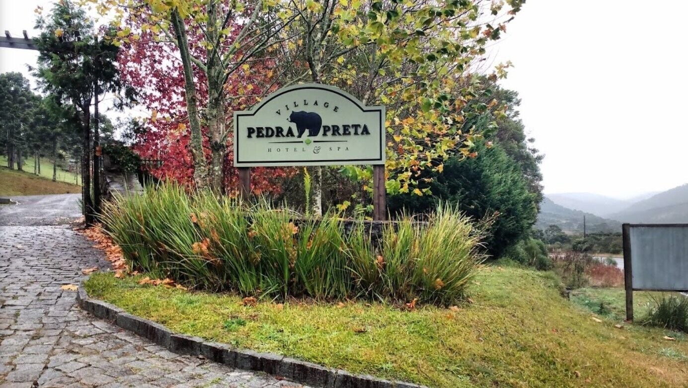 Schild des Pedrinho Preto Hotel & Spa, umgeben von Herbstlaub.