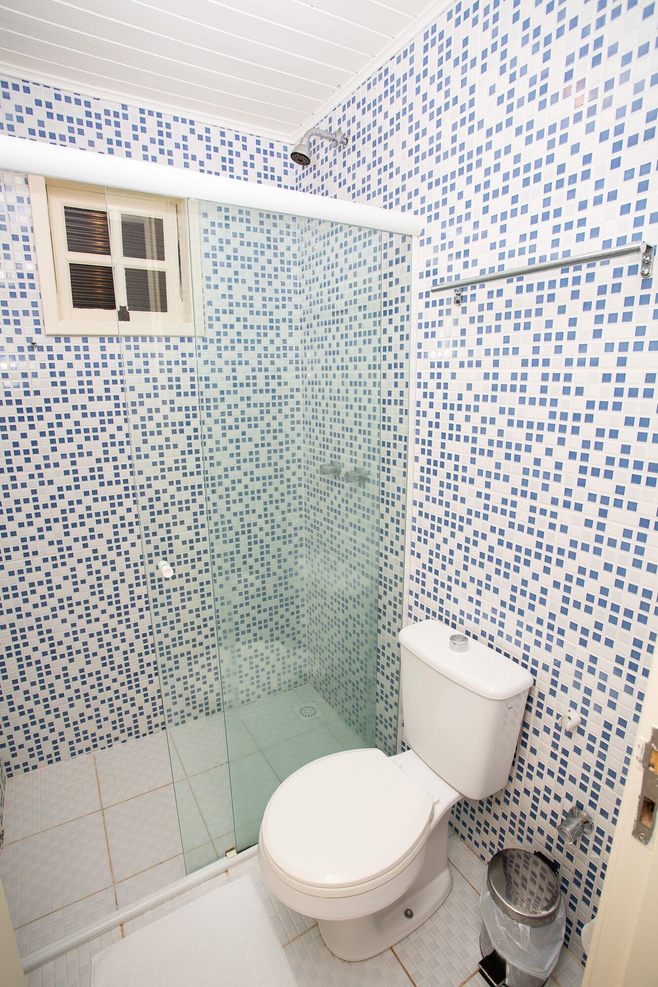 Casa de banho com chuveiro, sanita e janela.