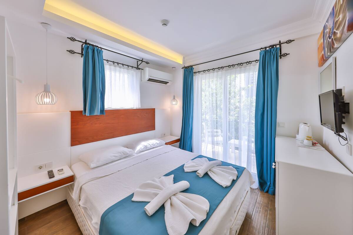 Una habitación de hotel con cama, mesita de noche y televisor en la pared.