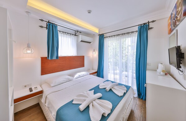 A hotel room with a bed, bedside table, and a TV on the wall. - Mina Apart Hotel (Kas)