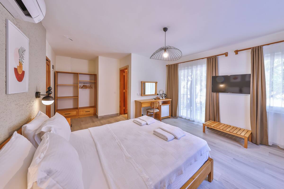 Una habitación de hotel con una cama grande, un escritorio, un televisor y un armario.