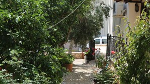 Un sendero en un jardín que conduce a un edificio con techo de tejas y fachada blanca.