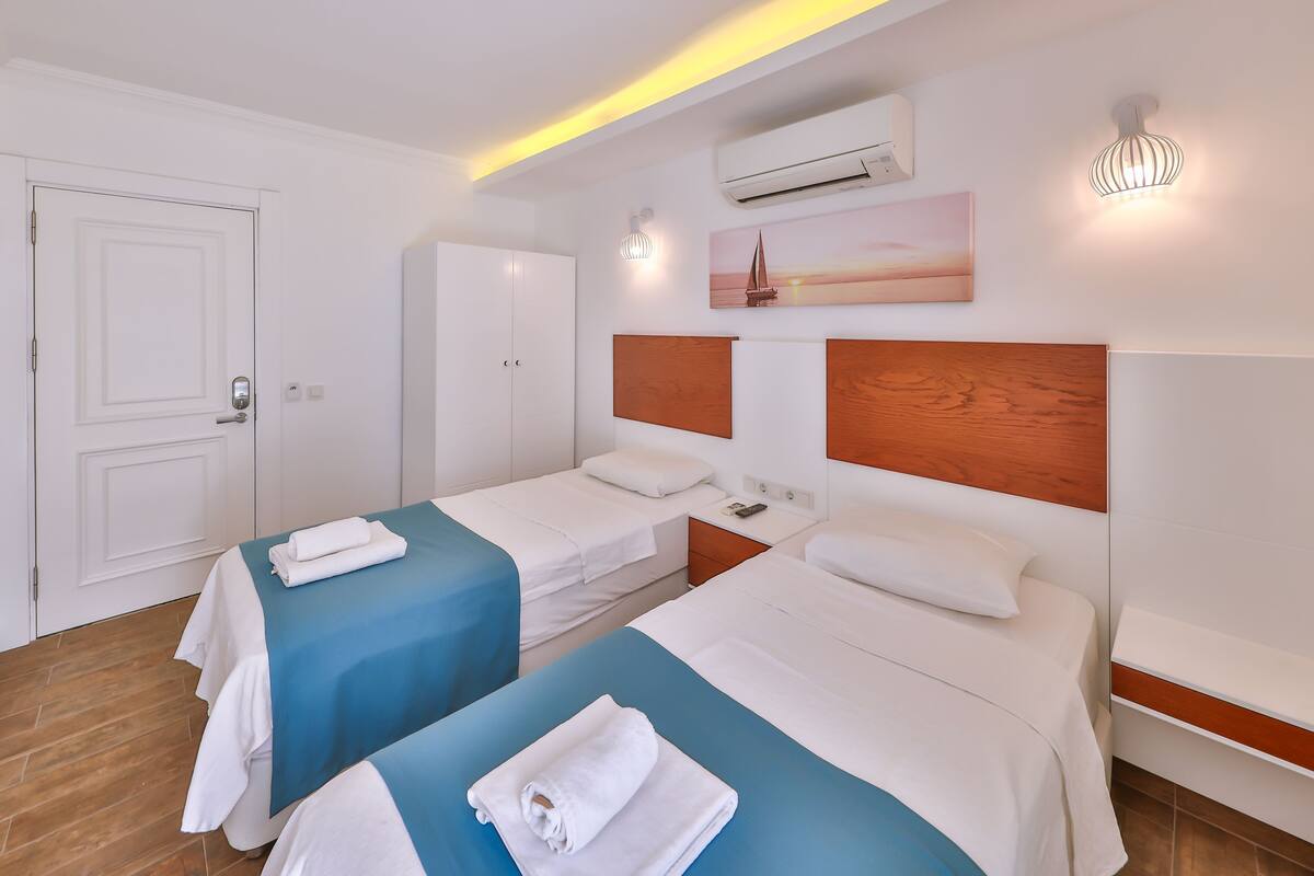 Una habitación de hotel con dos camas, un armario, un aire acondicionado y un cuadro en la pared.