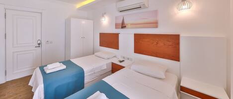 Une chambre d’hôtel avec deux lits, une armoire, un appareil de climatisation et un tableau au mur.