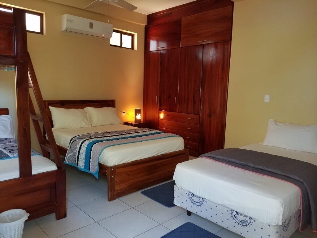 A bedroom with two beds, wooden headboards, a wardrobe, and an air conditioning unit.