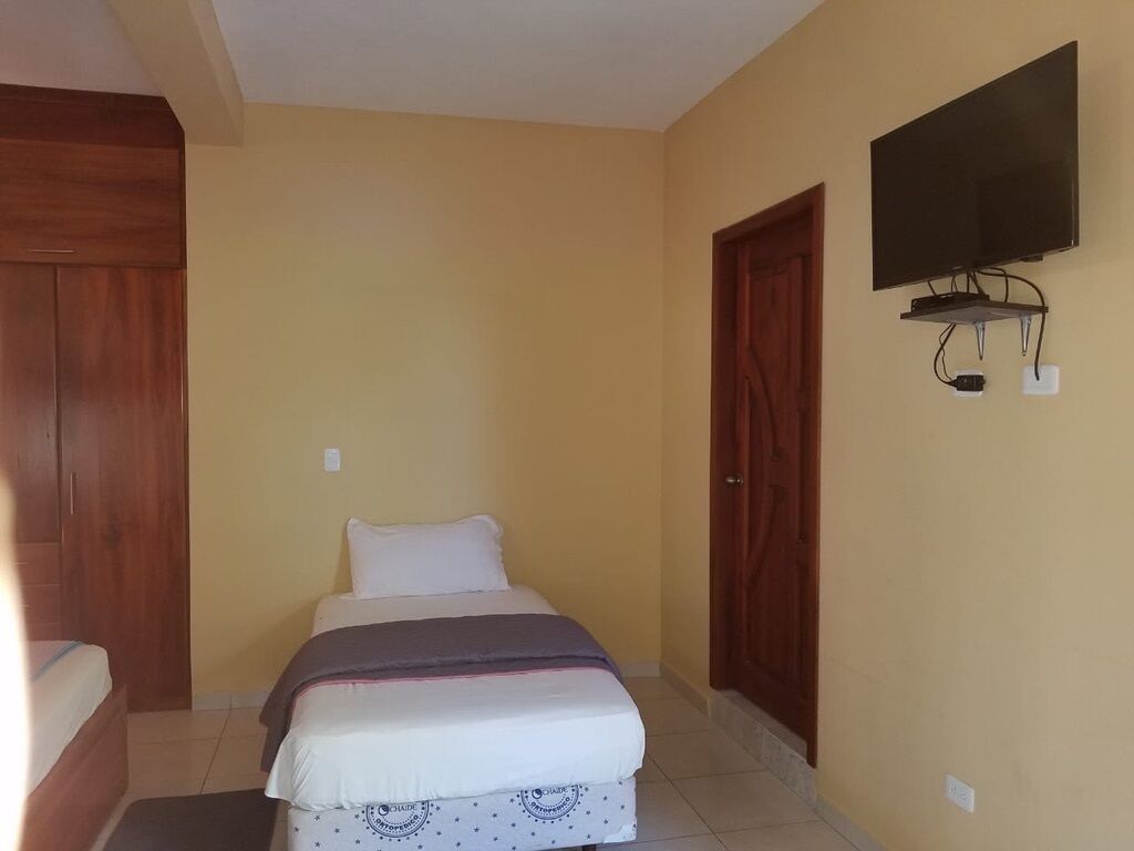 A bedroom with a bed, a television mounted on the wall, and wooden doors.