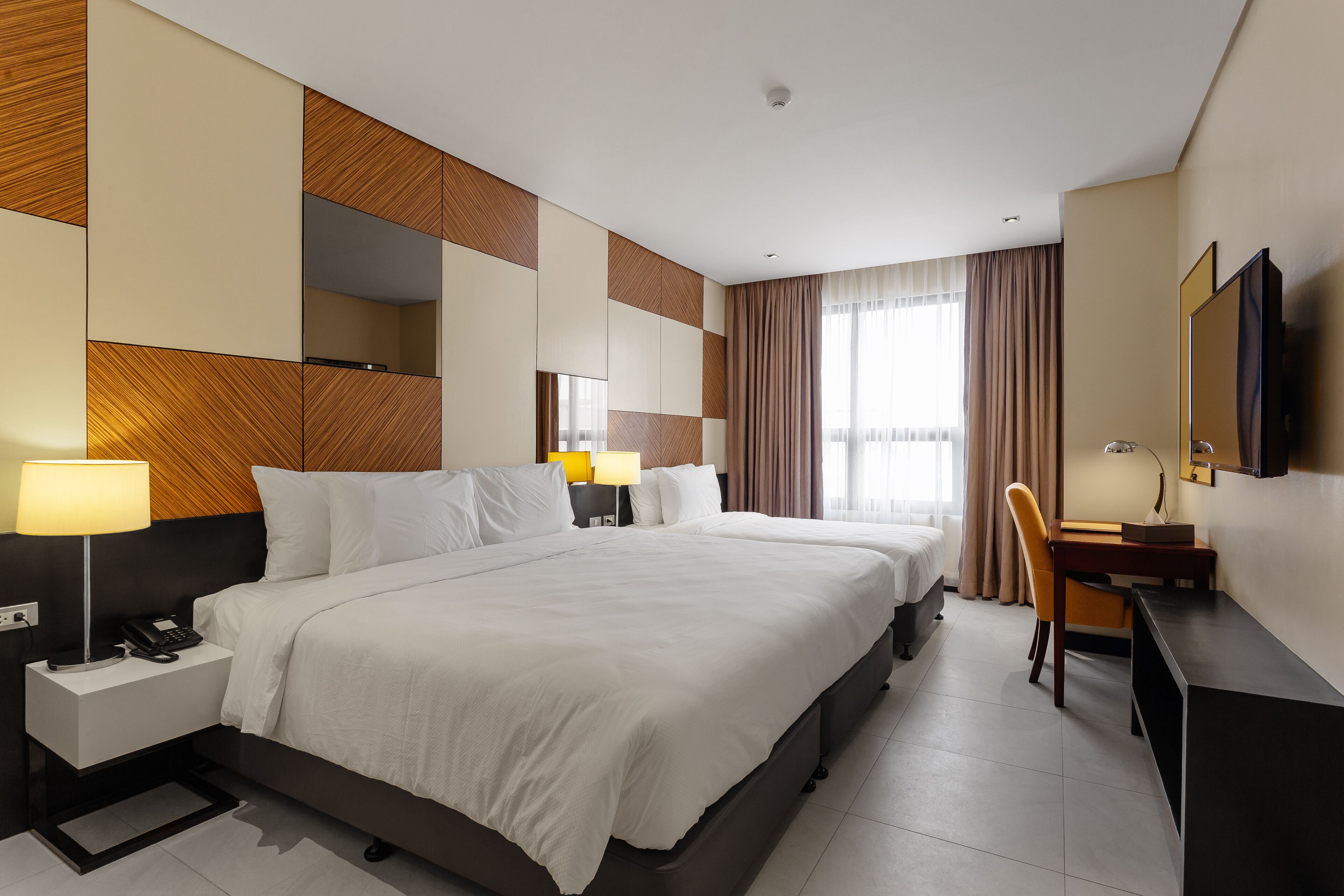 Ein Hotelzimmer mit einem großen Bett, Nachttischen, einem Schreibtisch und einem Sessel.