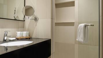 A modern bathroom with a glass shower enclosure, a black countertop, and a large mirror.