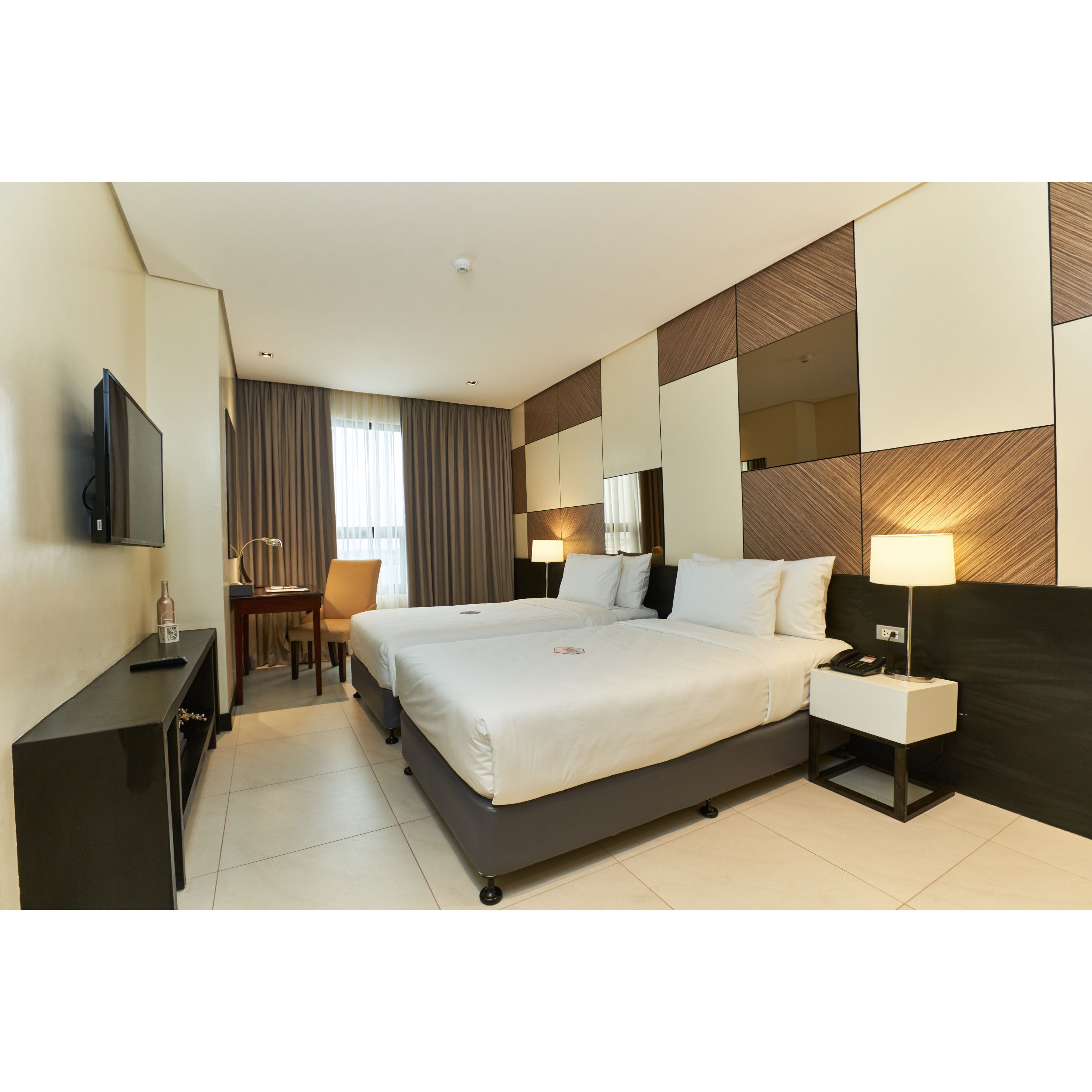 A modern hotel room with a large bed, bedside tables, a desk, and a television.