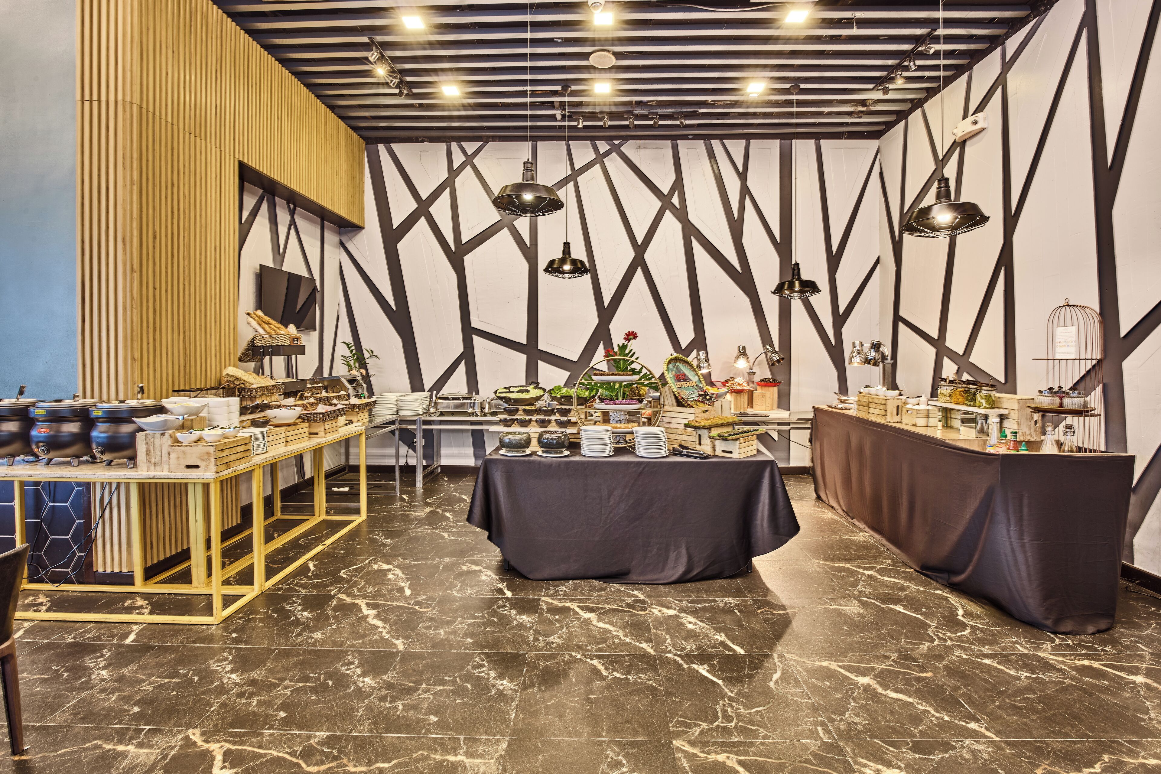 Un interior moderno con suelo de mármol, una mesa larga con mantel negro y una partición de madera con un televisor.