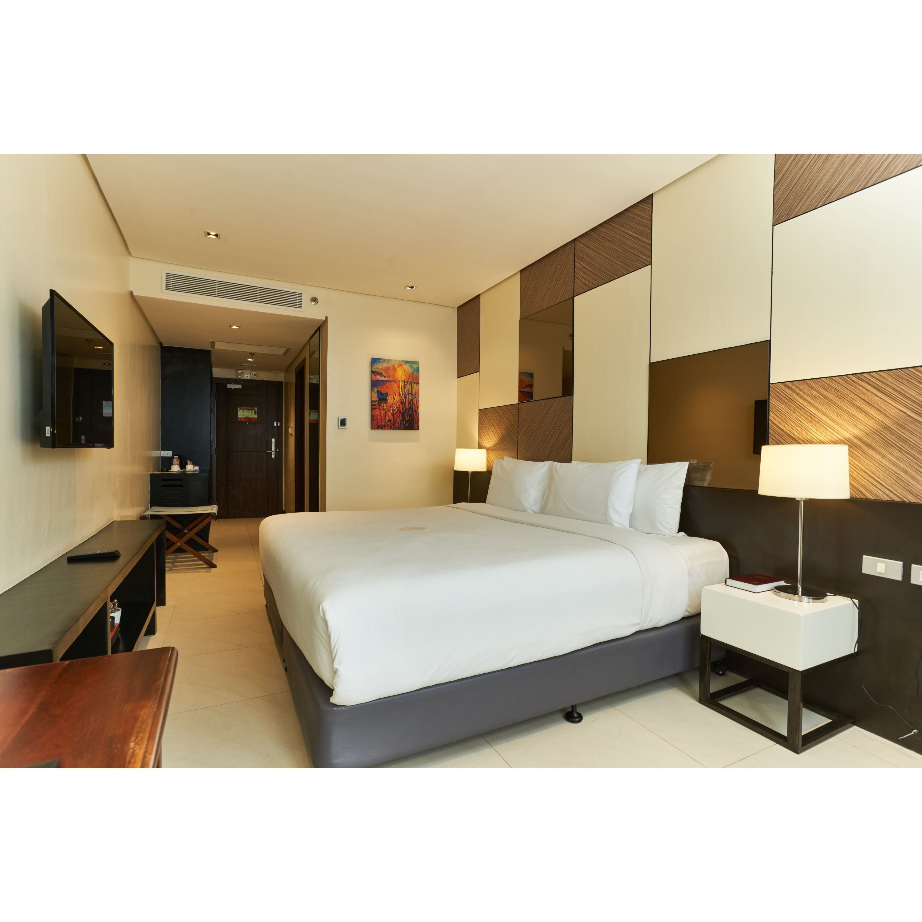 Una habitación de hotel moderna con una cama grande, mesitas de noche, un escritorio y un televisor.