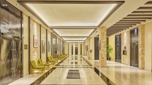 A long, well-lit hallway with a reflective floor, seating area with chairs, and artwork on the walls. - Summit Hotel Tacloban (Tacloban)
