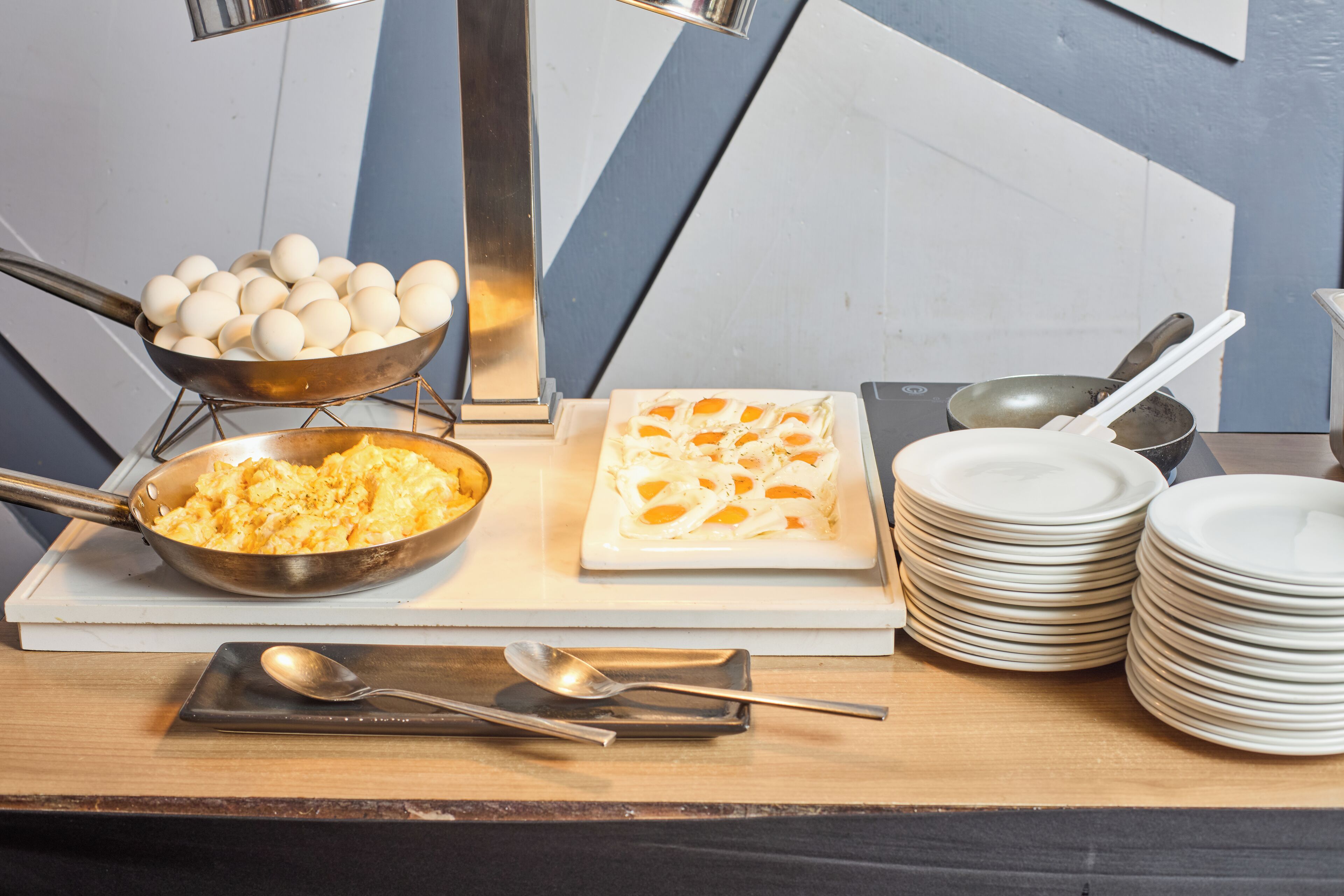 A breakfast buffet setup with scrambled eggs, a bowl of eggs, and a plate of scrambled eggs.