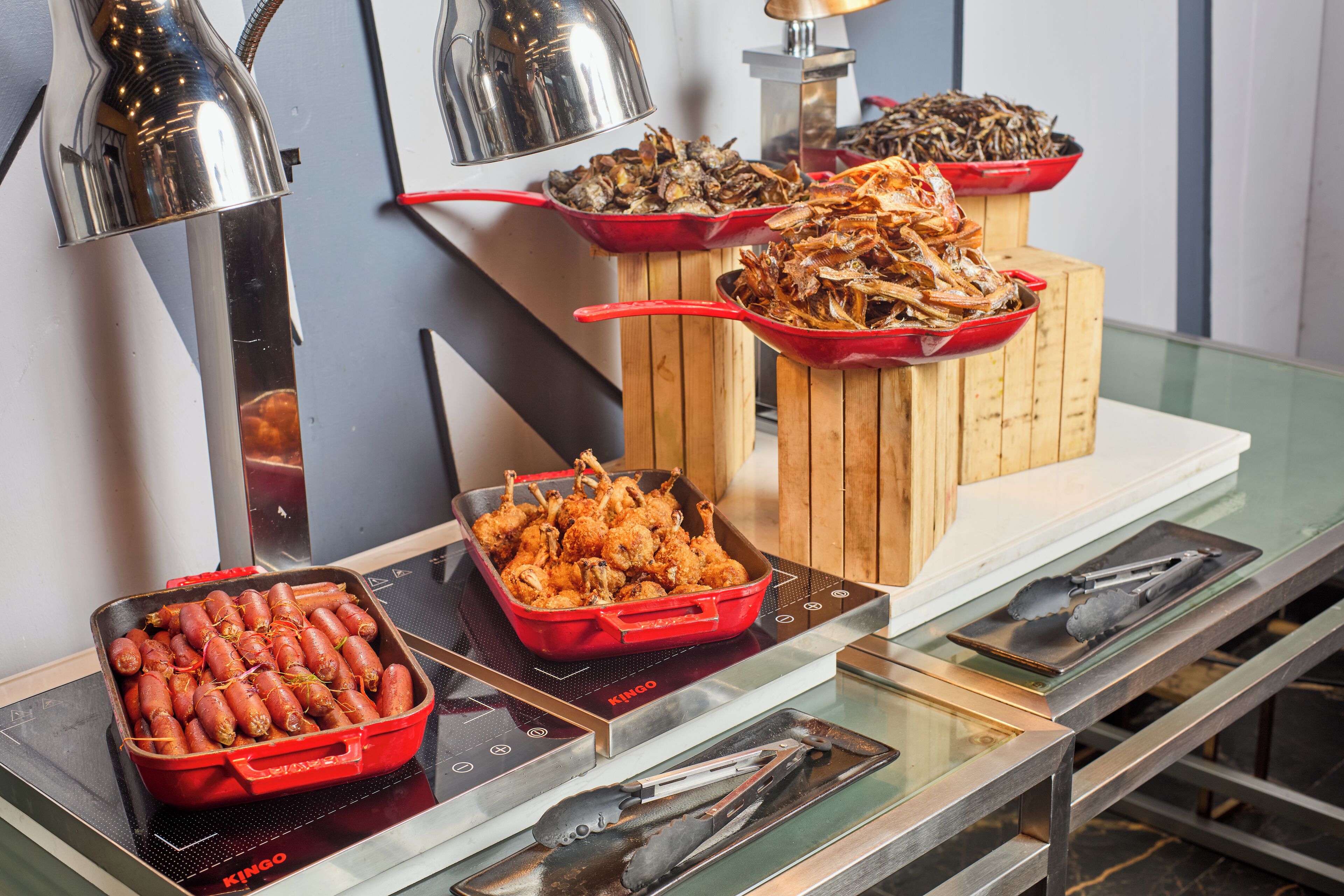 Ein reichhaltiges Buffet mit verschiedenen Speisen, darunter frittierte Gerichte und Meeresfrüchte, präsentiert auf einem Glastisch mit modernem Design.