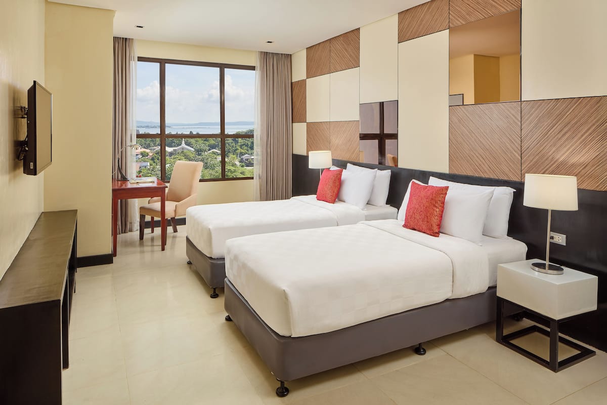 A hotel room with two beds, a desk, and a chair.