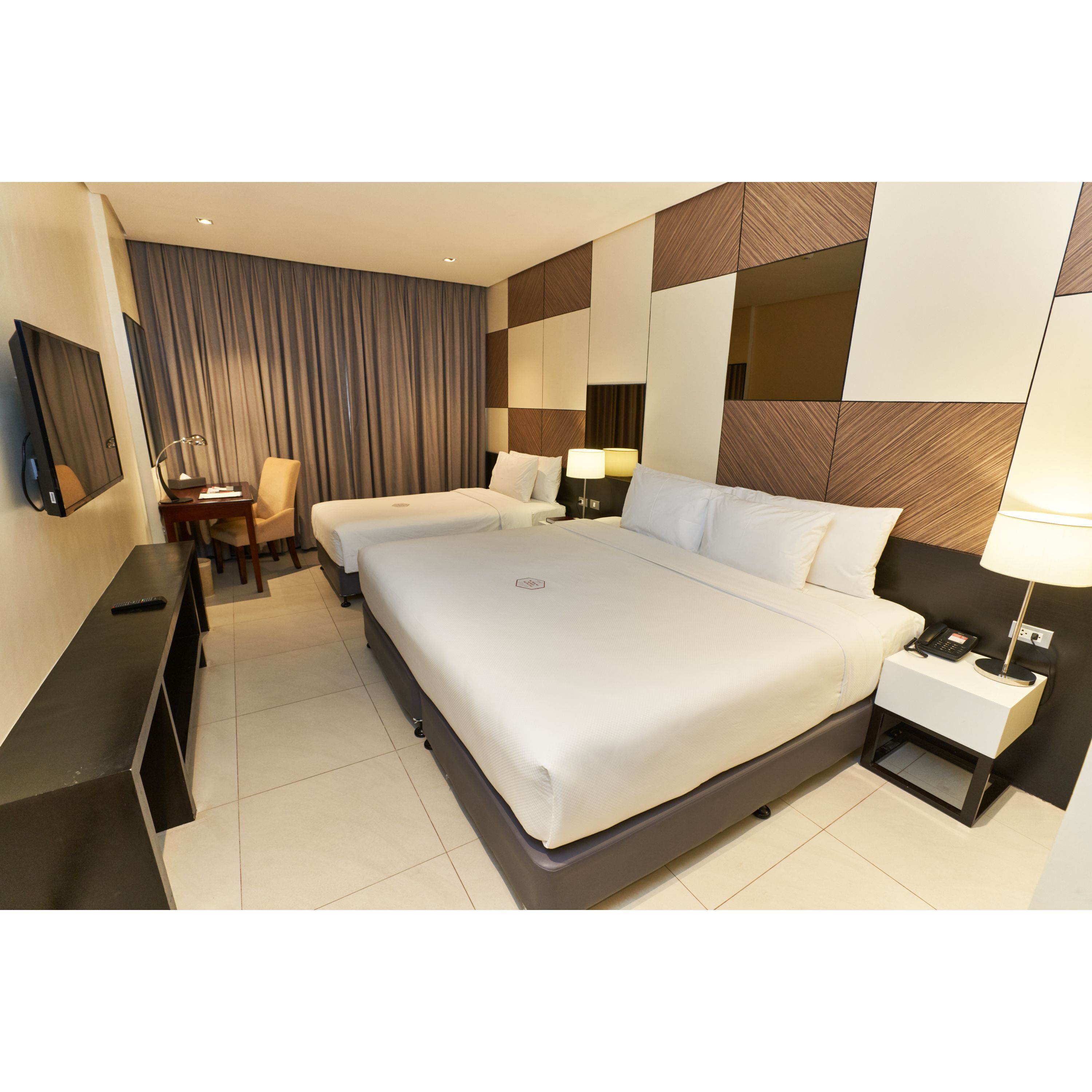 A hotel room with a large bed, bedside tables, a desk, and a chair.