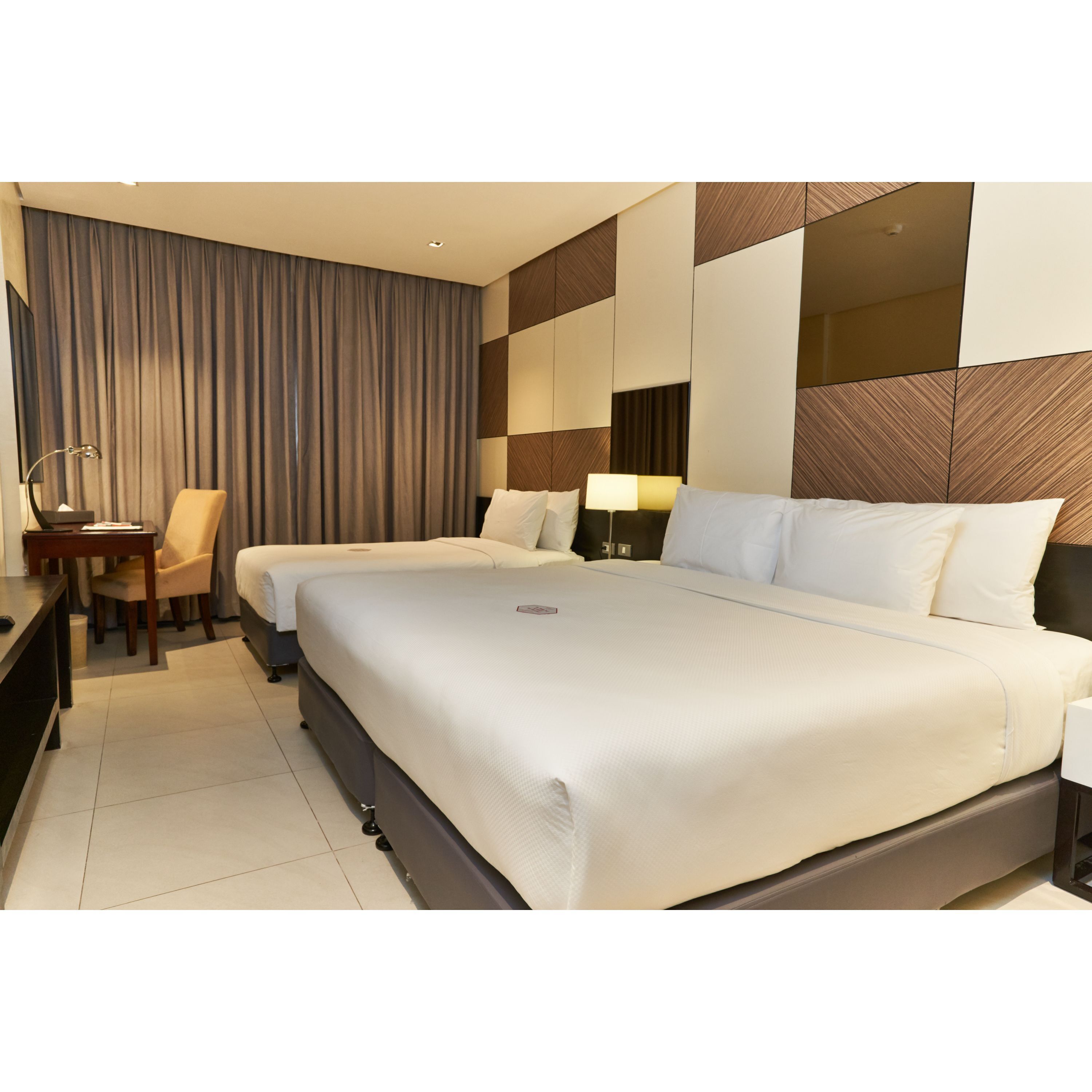 A hotel room with a large bed, a desk, and a chair.