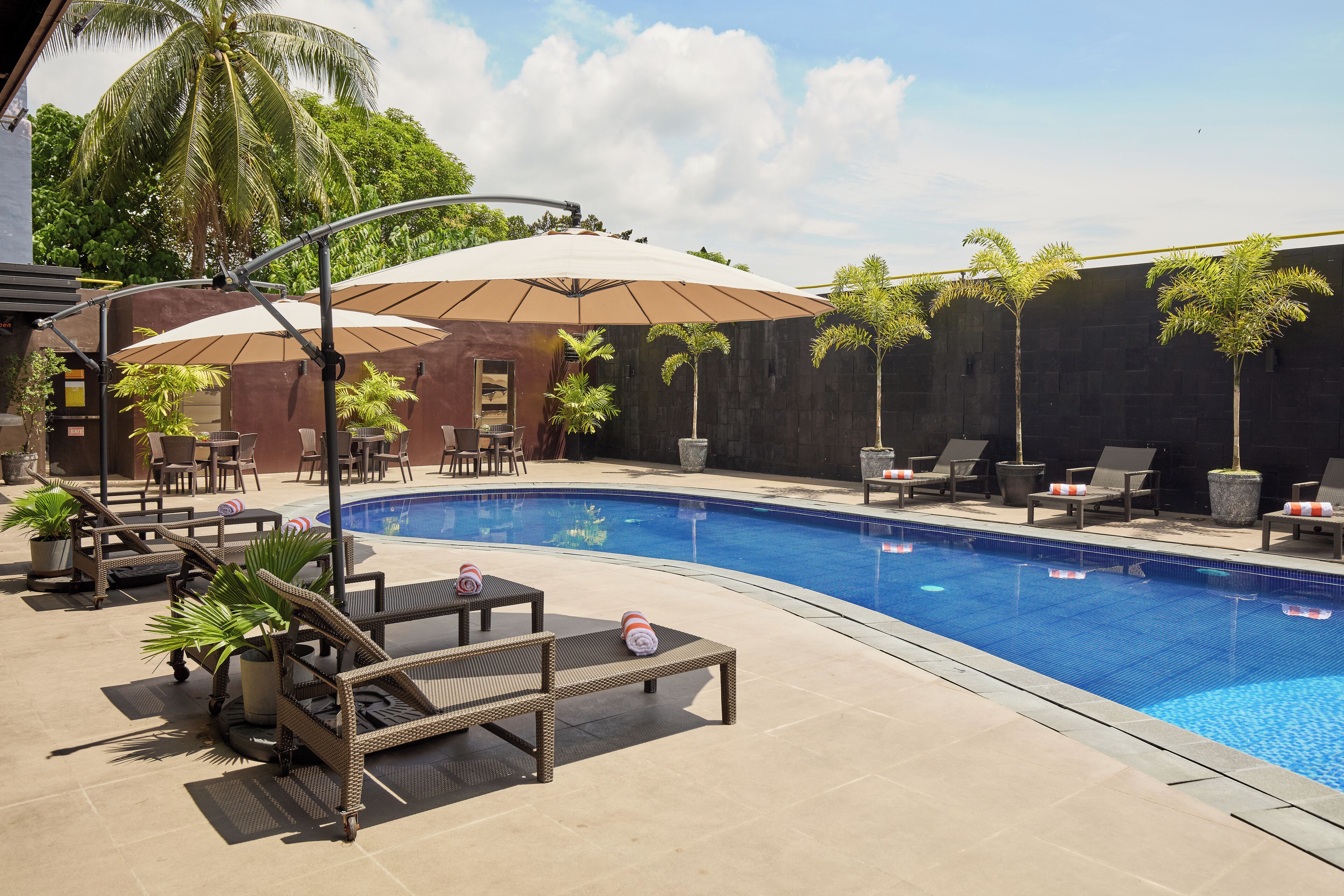 A swimming pool area with lounge chairs, umbrellas, and potted plants.