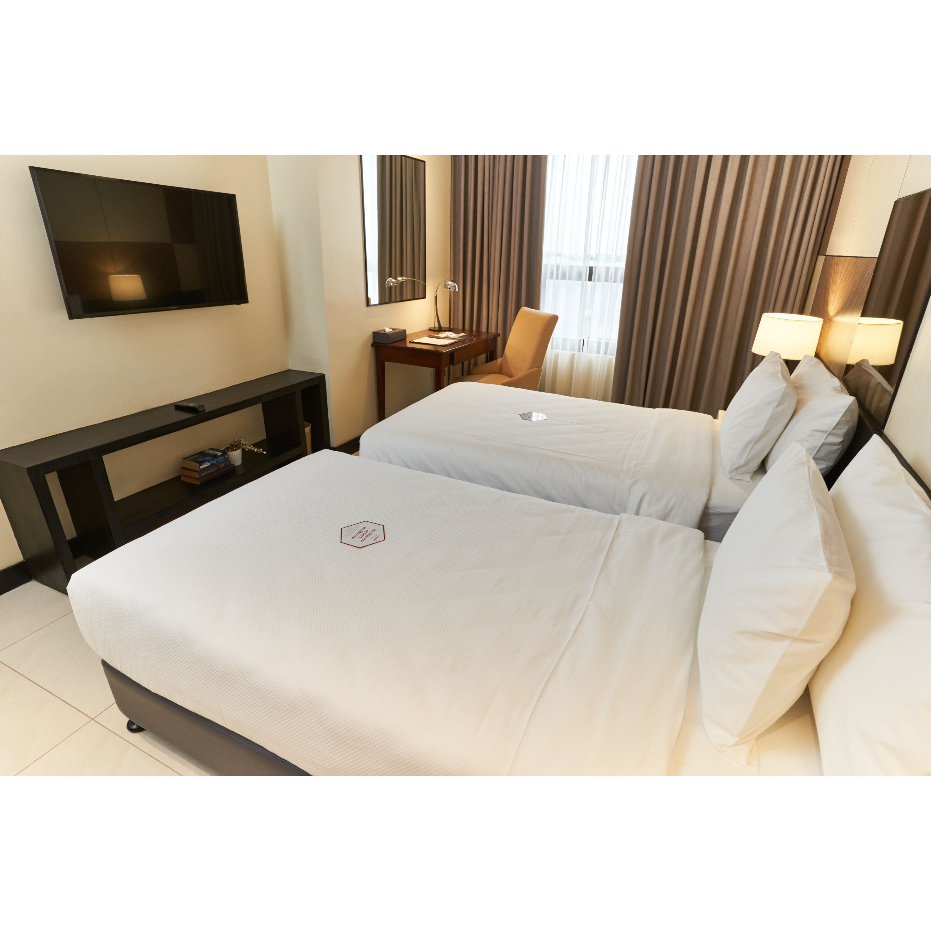 Una habitación de hotel con dos camas, televisión, escritorio y una silla.