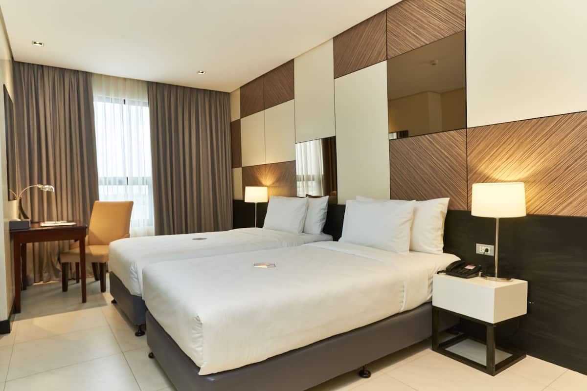 A hotel room with a large bed, bedside tables, a desk, and a chair.