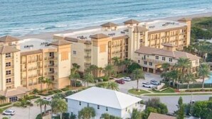 A beachfront hotel with multiple buildings, a swimming pool, and a parking area. - Modern, Cozy Efficiency Just Steps to the Beach! - Unit C (Cocoa Beach)