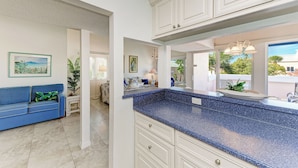 A modern kitchen with white cabinets, a blue granite countertop, and a view of the outdoors.