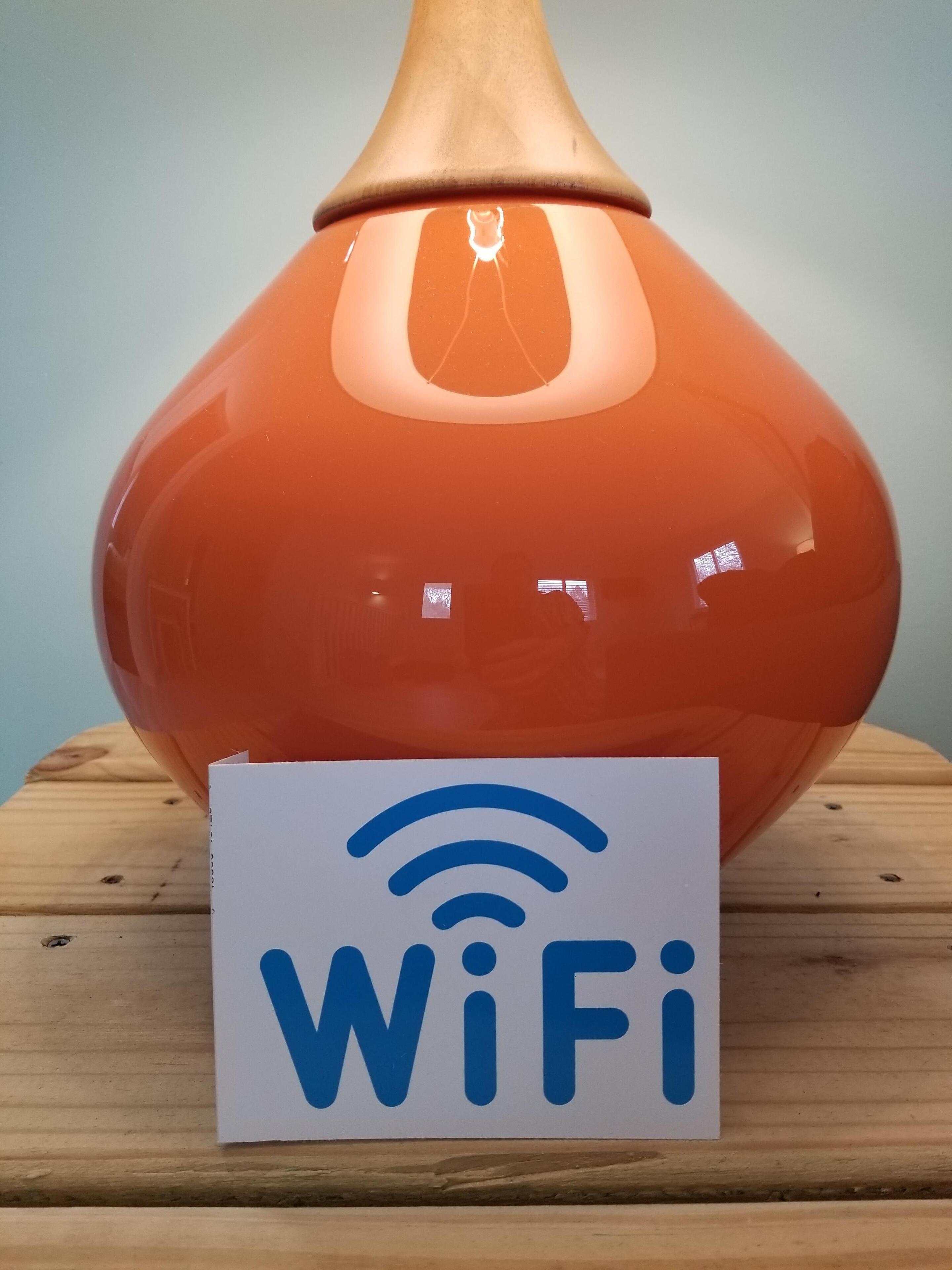 Et WiFi-symbol på et skilt foran en orange vase.