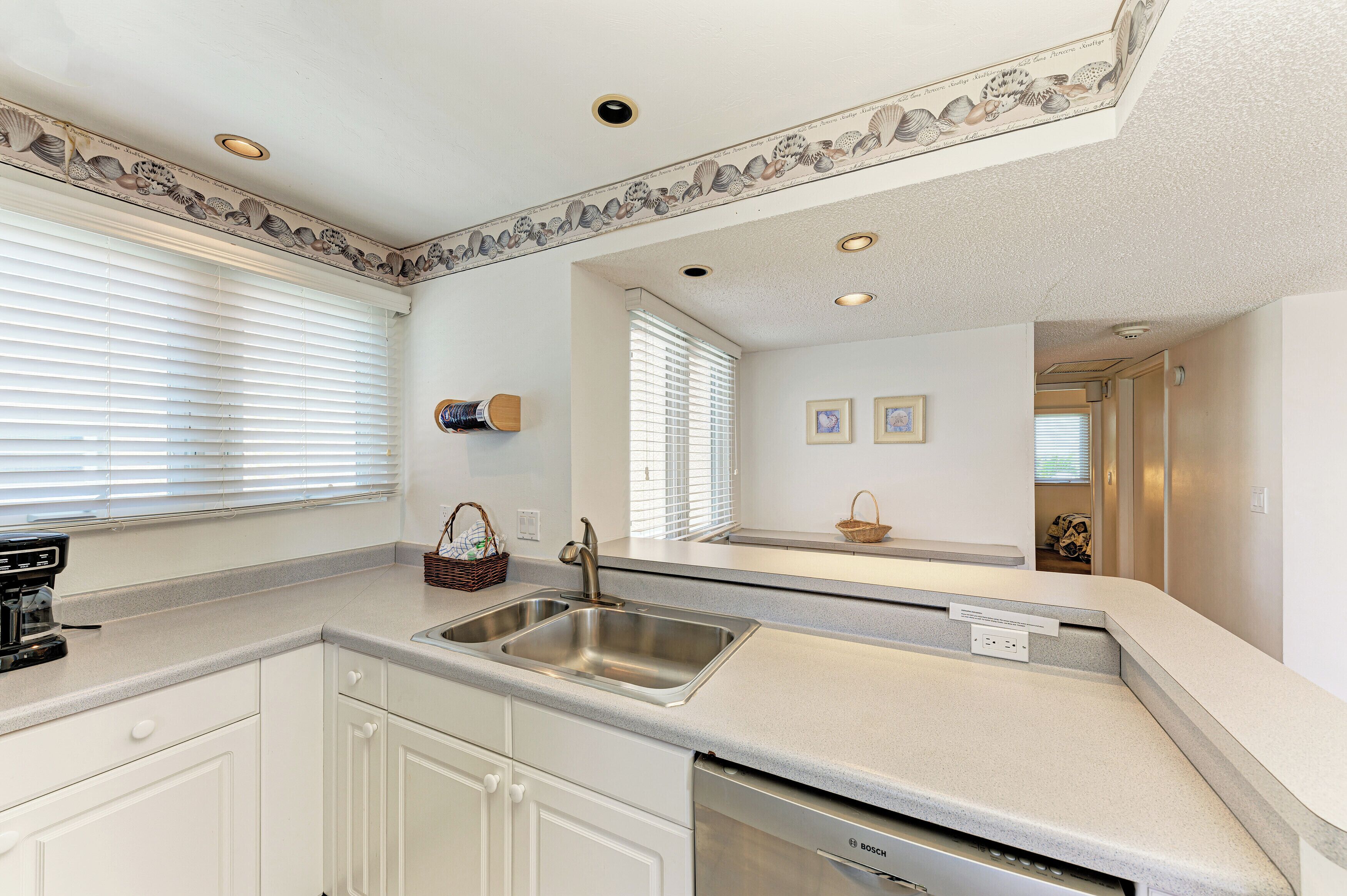 A modern kitchen with white cabinetry, a stainless steel sink, and a Bosch dishwasher.