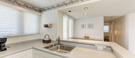A modern kitchen with white cabinetry, a stainless steel sink, and a Bosch dishwasher.